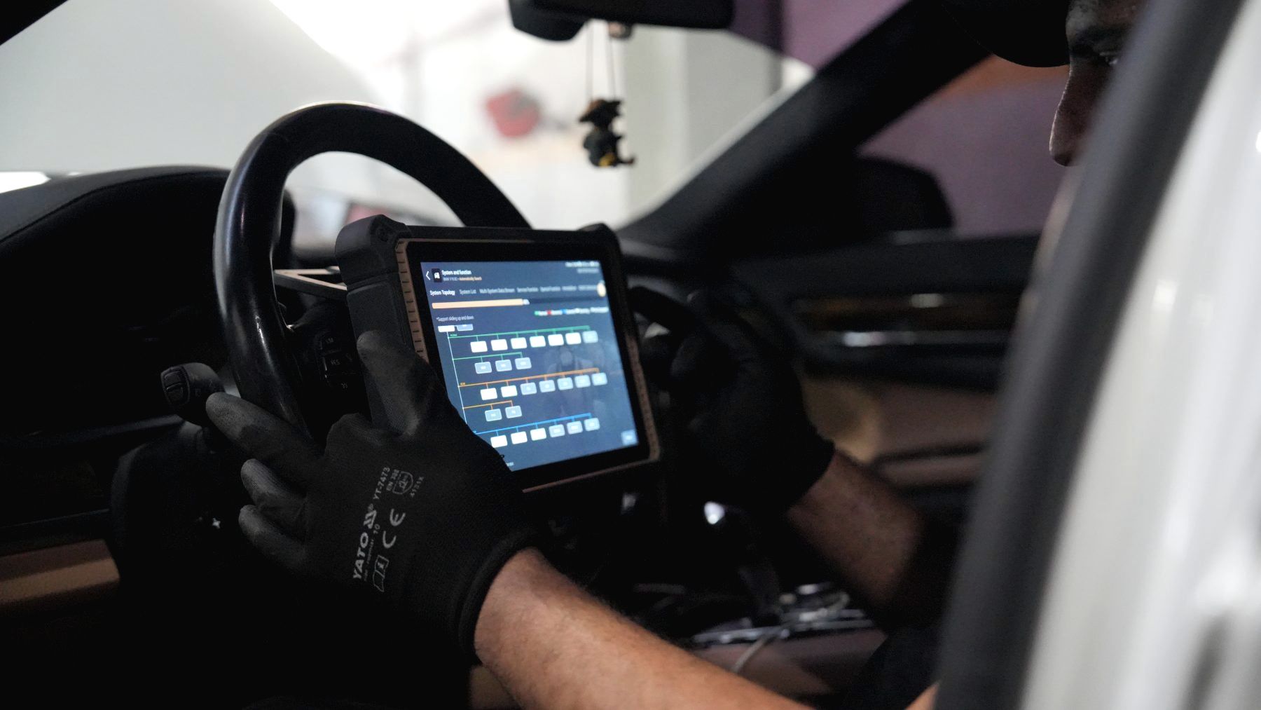 Technician reading live vehicle data on a diagnostic tablet from the driver's seat