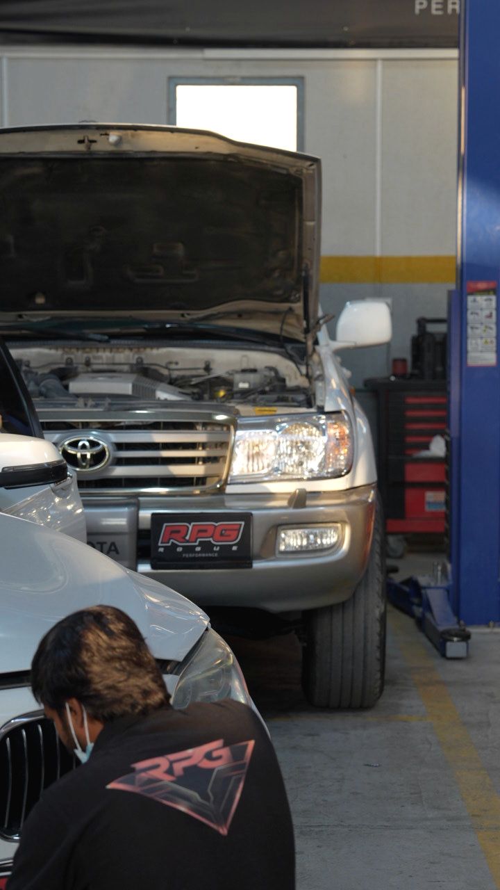 Technician working on an open Land Cruiser engine bay at Rogue Performance Garage