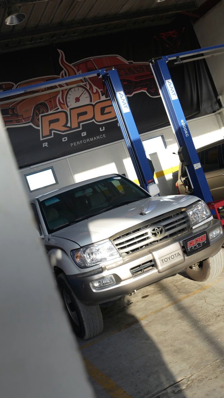 Silver Toyota Land Cruiser raised on a two-post lift