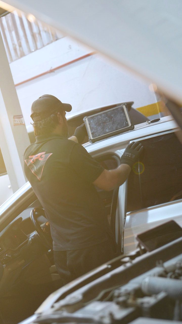 Technician using a diagnostic tablet at the open door of a car