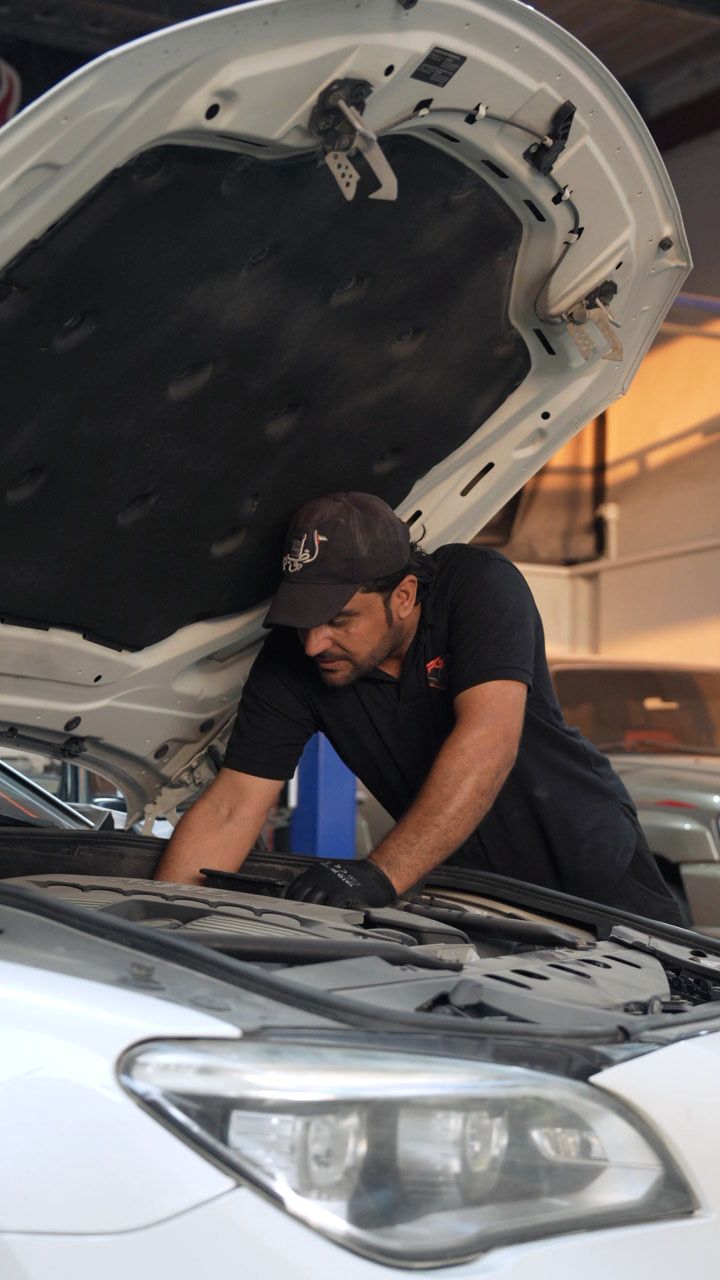 Technician in an RPG shirt working under the bonnet of a car